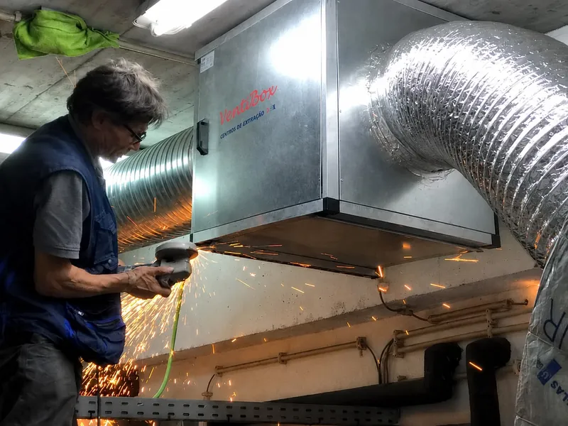 Técnico da MDM a trabalhar com rebarbadora sob um grupo de extração Ventilbox, com faíscas.