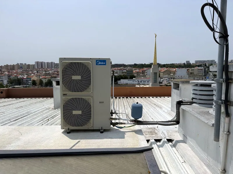 Unidade de dois ventiladores com vaso de expansão numa cobertura de chapa sobre os telhados de Moscavide.