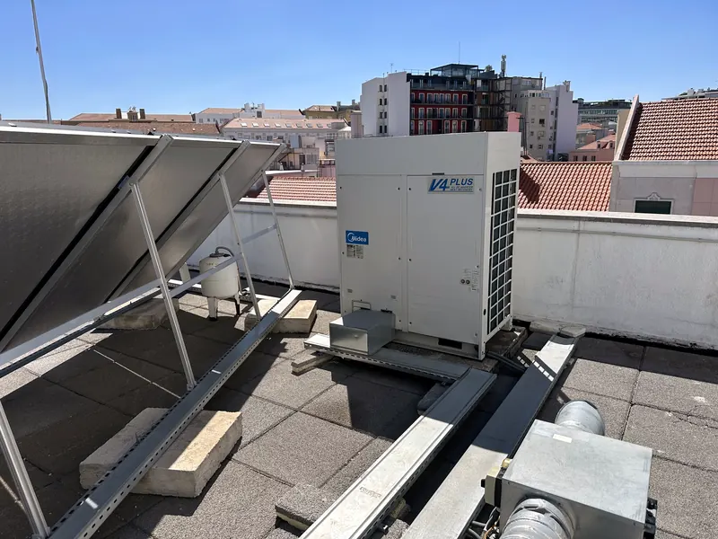 Unidade exterior VRF Midea numa cobertura de Lisboa, ao lado de coletores solares.