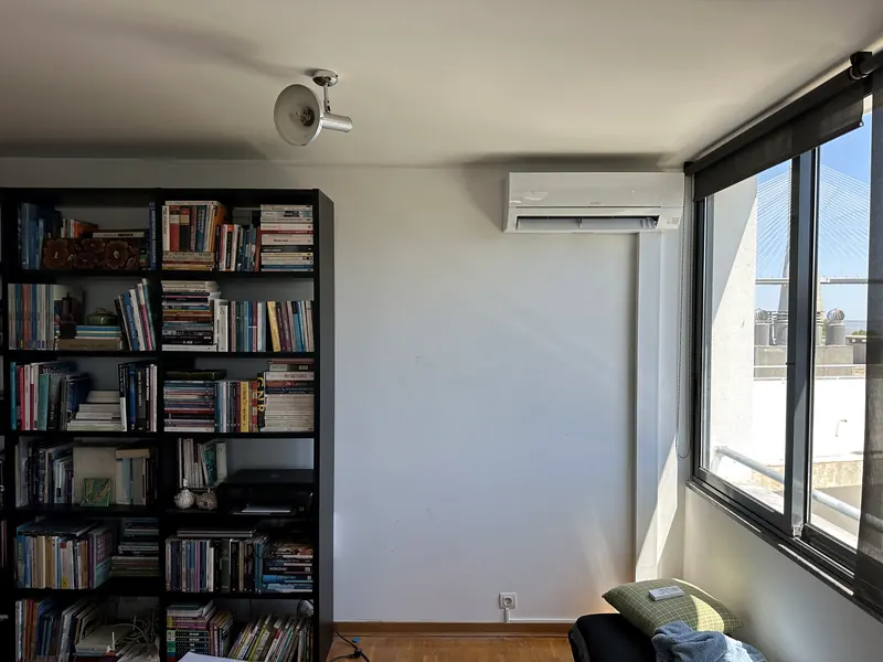 Unidade mural numa sala com estante de livros e a Ponte Vasco da Gama à janela.